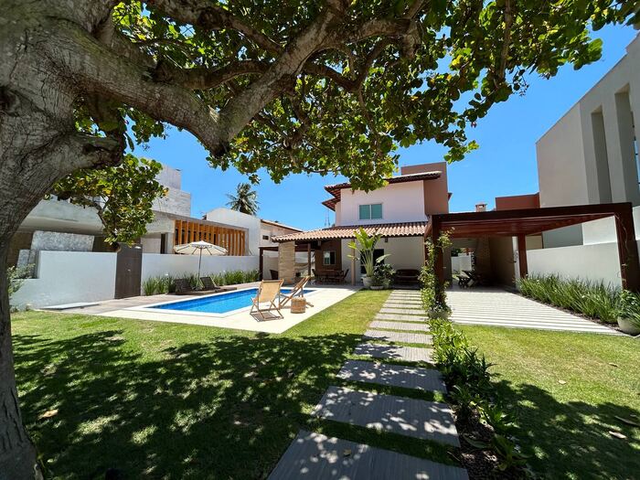 Jardim com árvore frondosa e piscina ao fundo